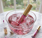Pink lip gloss bottle in a glass with ice cubes on a marble surface